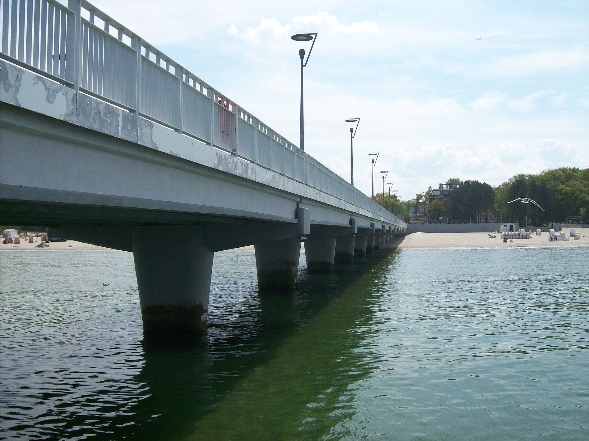 Molo w Kołobrzegu od strony wody, w tle plaża i kosze plażowe